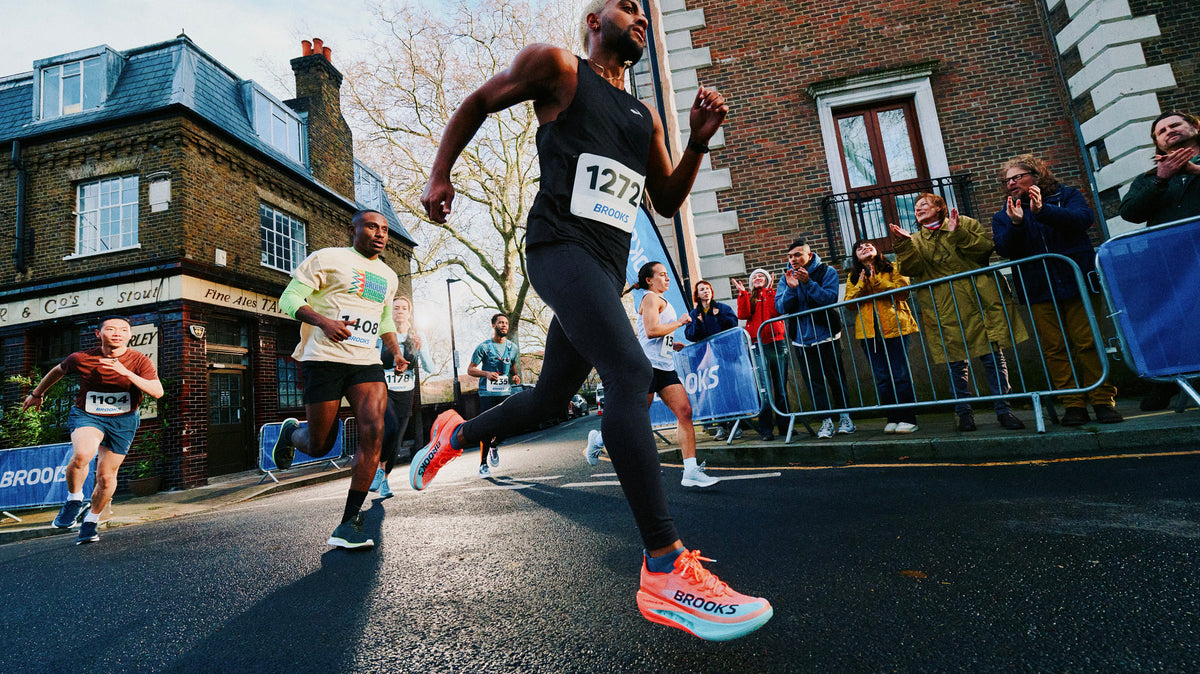 Runner lacing a plated super shoe next to a cushioned daily trainer before a tempo workout.