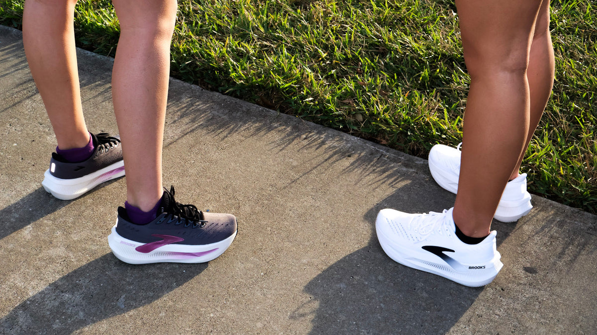Runner lacing one high‑stack cushioned shoe and one lightweight responsive shoe side by side before a workout.