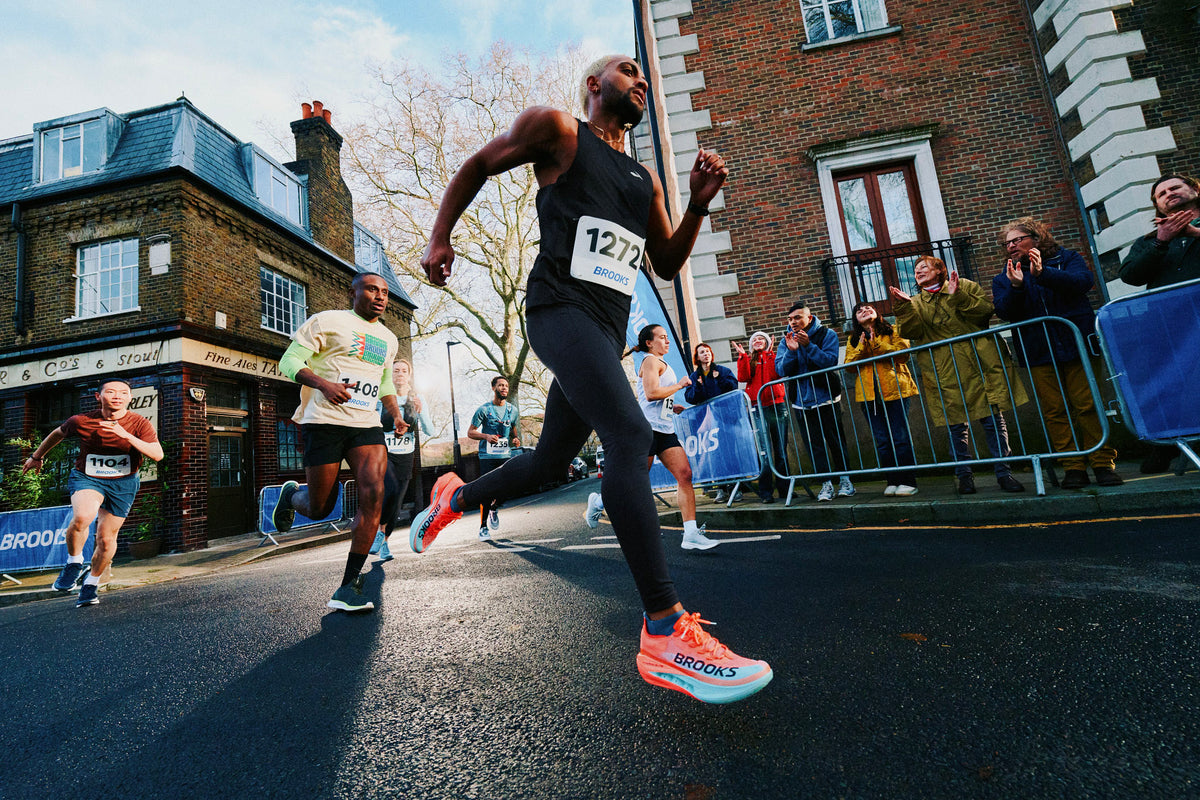 Runner lacing a plated super shoe next to a cushioned daily trainer before a tempo workout.