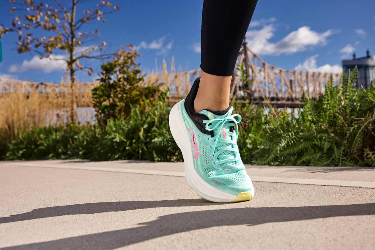 Runner’s rearfoot close-up showing padded collar and structured heel counter while tightening a gusseted tongue for secure lockdown.
