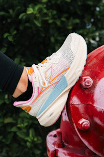 Runner stepping from wet asphalt onto packed dirt showing outsole rubber and mixed-depth lugs in action.