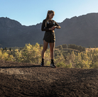 Trail runner checking a Garmin fēnix 9 Pro smartwatch in a mountain setting