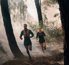 Two trail runners running through wooded terrain