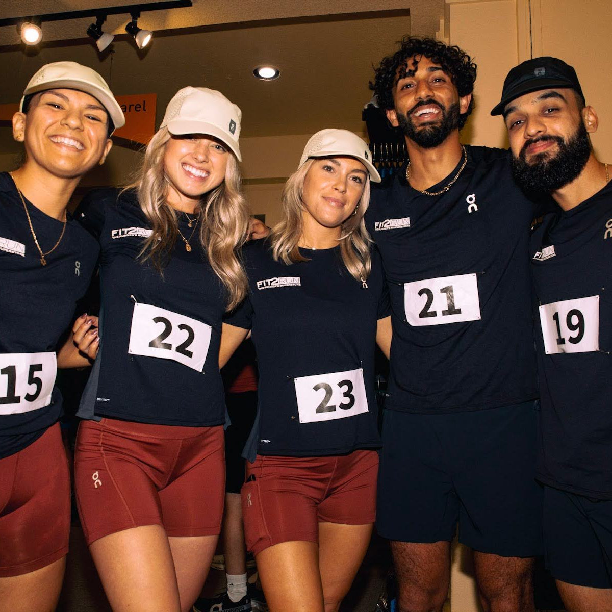 Five people wearing matching dark blue shirts with numbers on a blurred indoor background